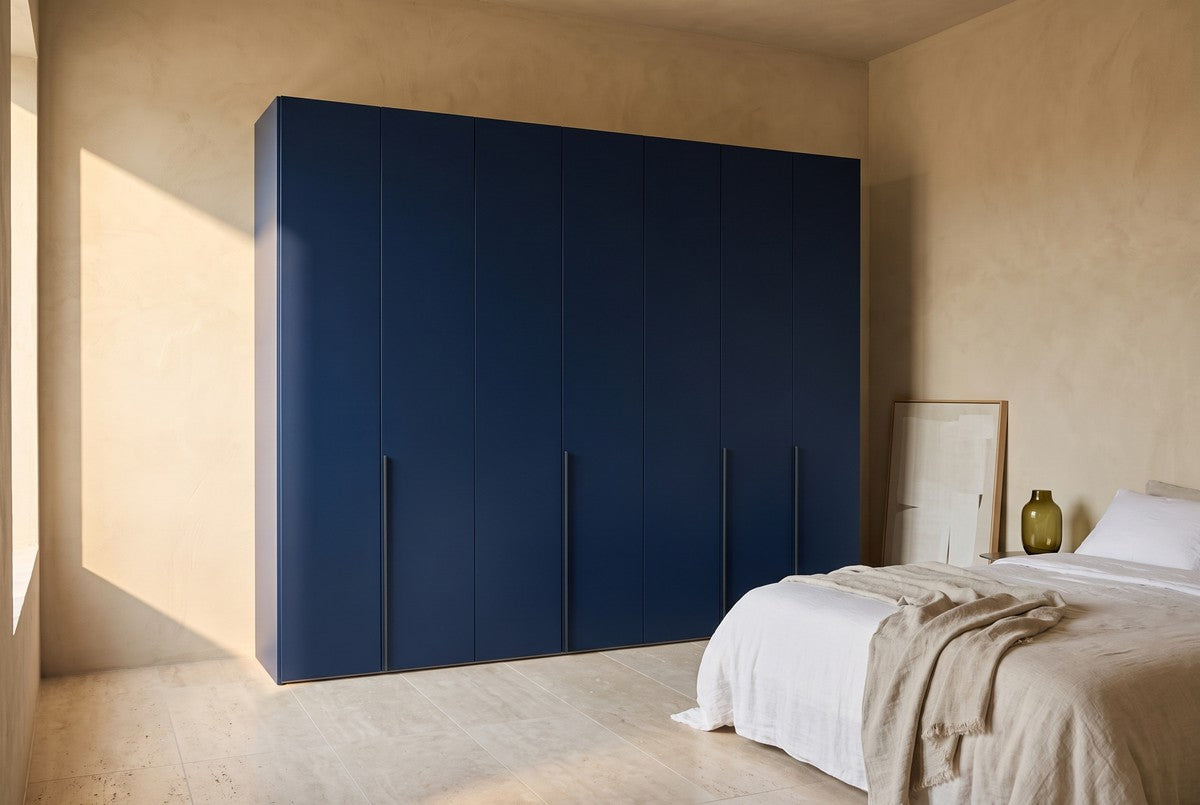Libeccio-kledingkast in Matlak · Blu Oltremare in een lichte slaapkamer (AI-sfeerbeeld)