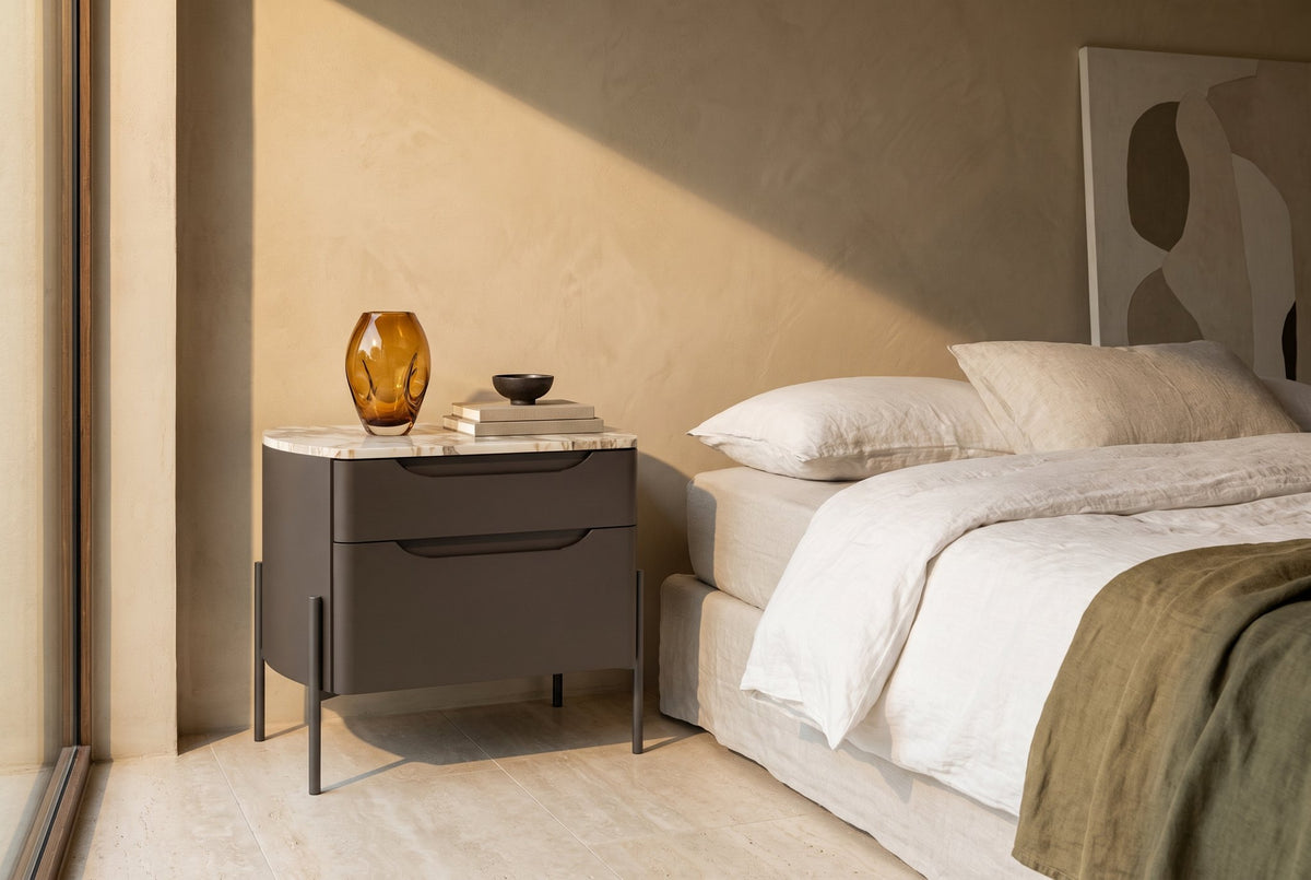 Ambra nachtkastje met 2 laden – Matlak · Cacao / Decor · Pietra Fiorentina · Metal Gray – in een slaapkamer (AI-beeld)